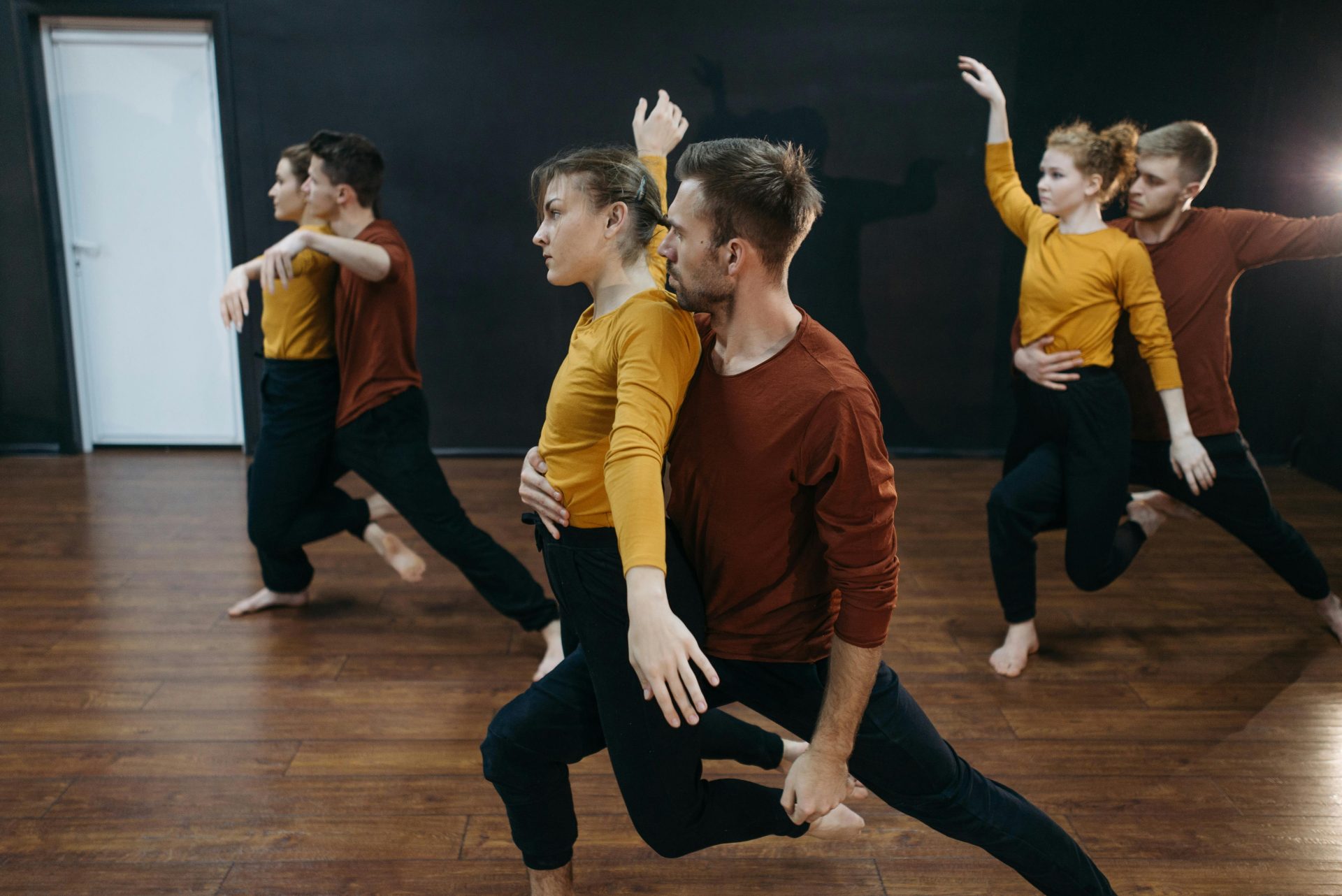 Grupo de bailarines practicando movimientos contemporáneos en un estudio interior.